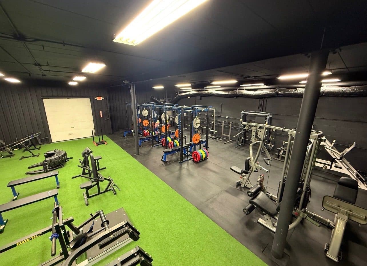 Wide view of the gym: benches, racks, and machines on turf