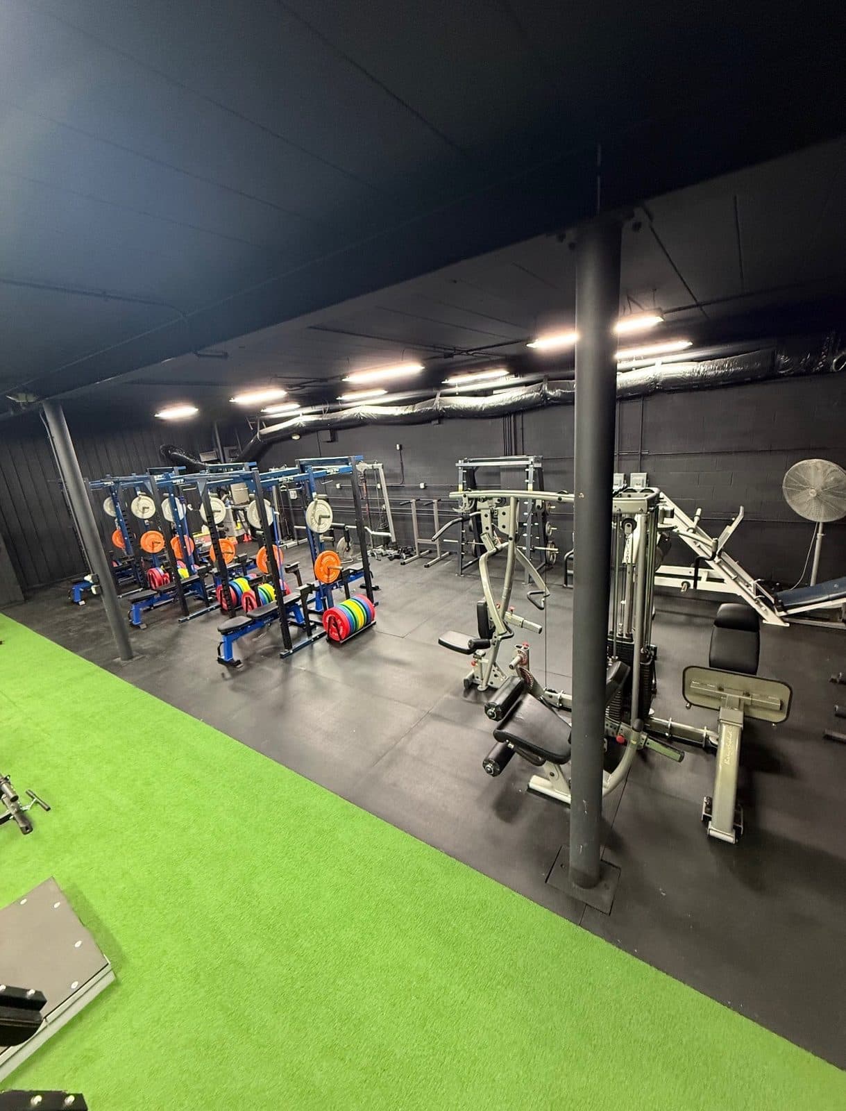 Squat racks and machines on turf in the Nukes Warehouse gym