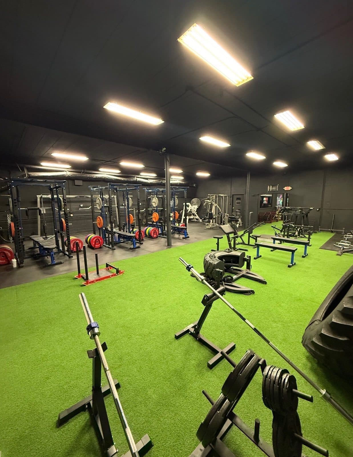 Barbells racked on the turf with a flipping tire in the corner